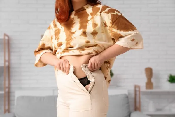 Image of woman trying to do her trousers up after pregnancy weight gain Swansea