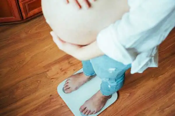 Image of woman weighing herself and experiencing weight gain through pregnancy Swansea